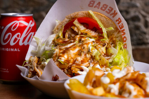 Kebap Menü mit Fleisch, Salat und Sauce in einer Box serviert, dazu Pommes und eine Cola Dose
