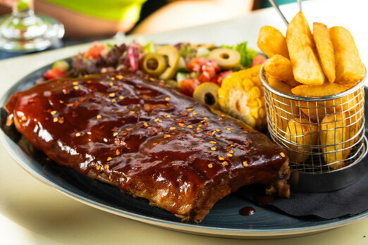 Spare Ribs mit BBQ-Sauce, Pommes und Gemüse auf einem Teller
